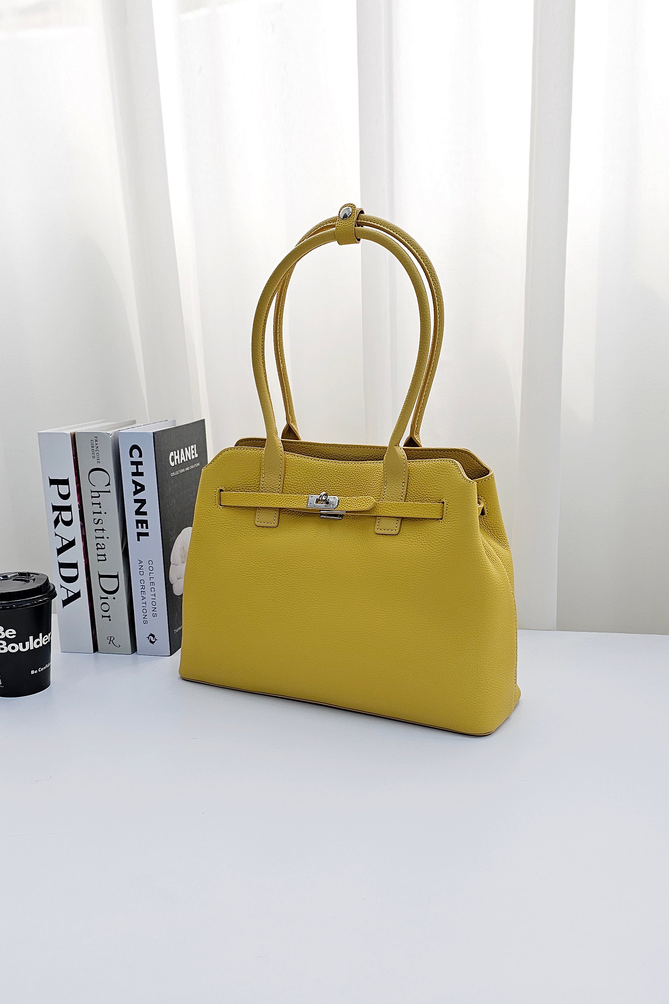 A bright yellow leather handbag with double top handles and a front strap closure