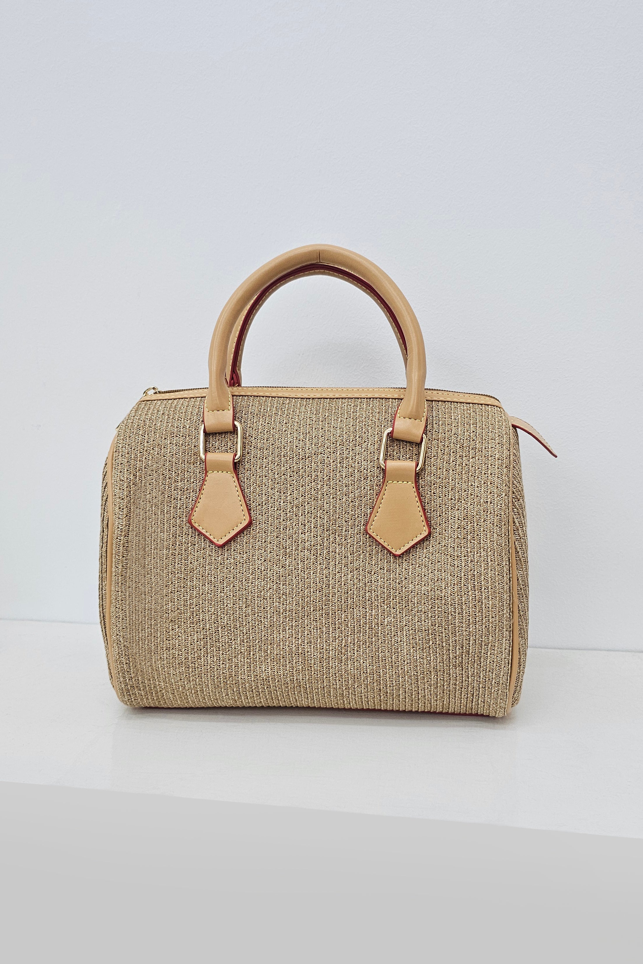 A structured straw handbag with tan leather handles and trim