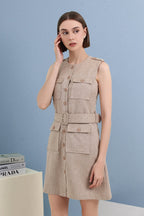 A woman modeling a sleeveless beige linen-look mini dress with a matching belt, button front, and flap pockets