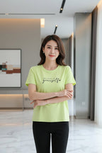 A woman wearing a light lime green short-sleeve t-shirt with 'believe in yourself' printed on the chest