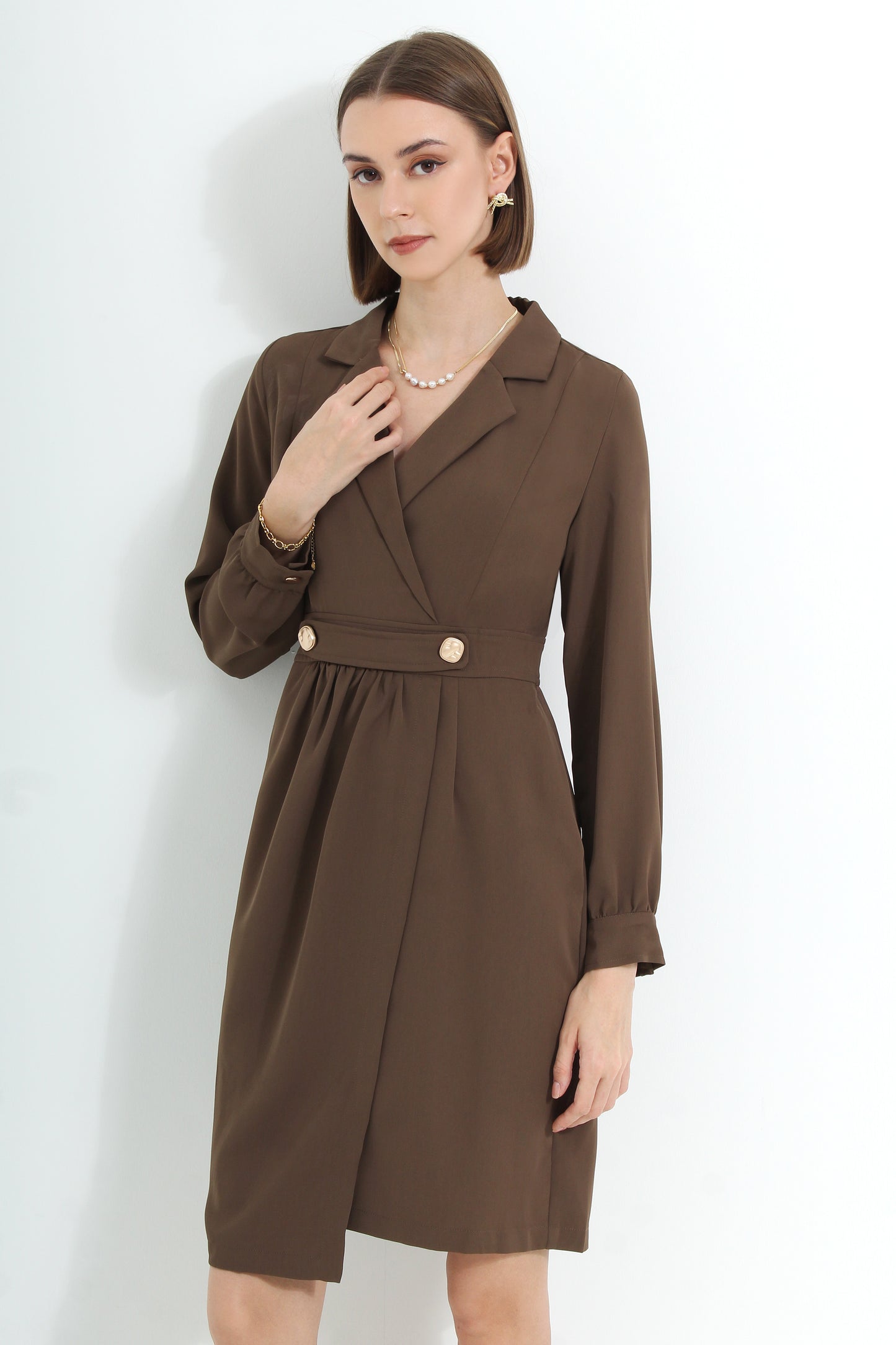 A woman wearing a brown knee-length dress with long sleeves and a V-neckline
