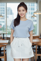 Woman wearing a light blue shirt and white skirt in a restaurant setting