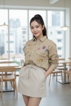 Woman in a beige outfit with floral embroidery in an indoor setting