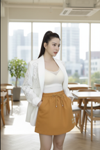 Woman in a white blazer and mustard skirt standing in a modern office setting.