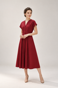 A woman modeling a short-sleeve, V-neck midi dress in deep burgundy red