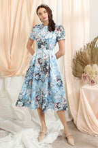 A woman standing in a vintage floral dress with pleats