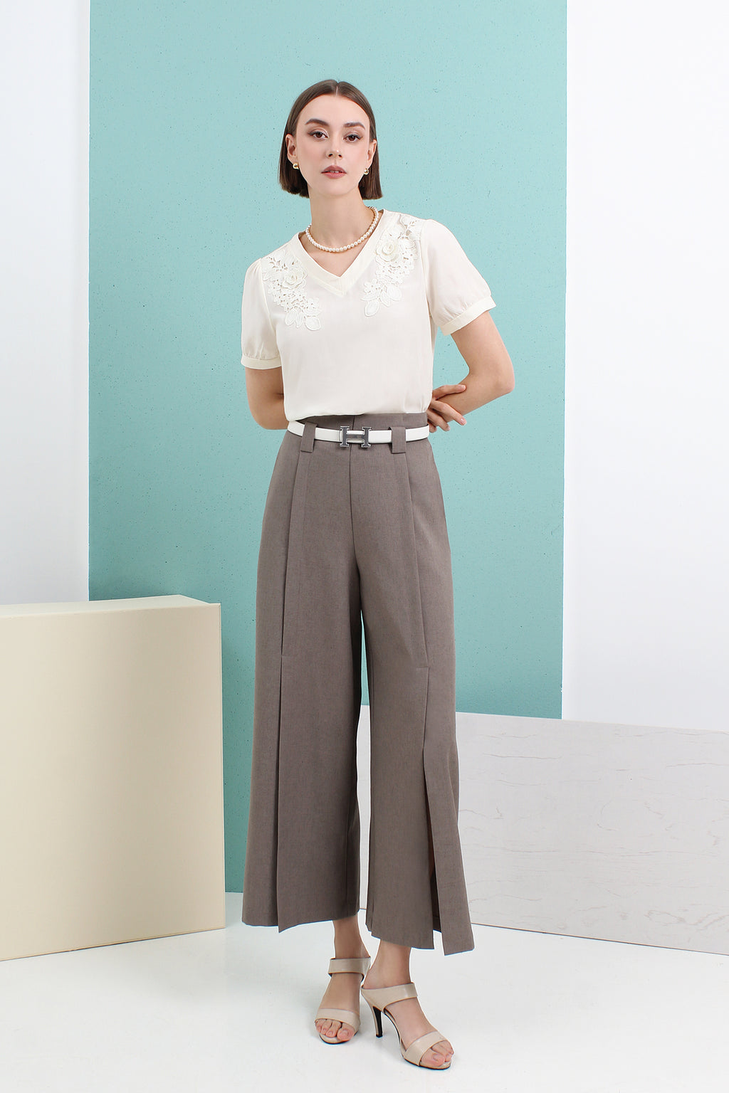 A model wearing a beige knit top and gray wide-leg pants