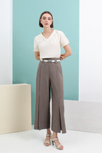 A model wearing a beige knit top and gray wide-leg pants