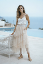 A woman wearing a layered tulle midi skirt in a light blush-beige tone