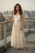 A woman with cream-colored sleeveless lace maxi skirt with a matching cream top. 