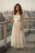 A woman with cream-colored sleeveless lace maxi skirt with a matching cream top. 