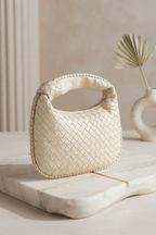 A cream-colored woven leather handbag with a top handle