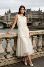 A woman models a sleeveless white lace and tulle midi dress
