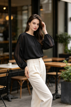 A woman wearing a black sheer long-sleeve blouse.