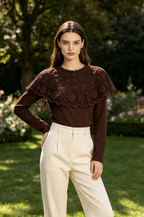 A woman wearing a dark brown long-sleeve top with a wide lace ruffle collar