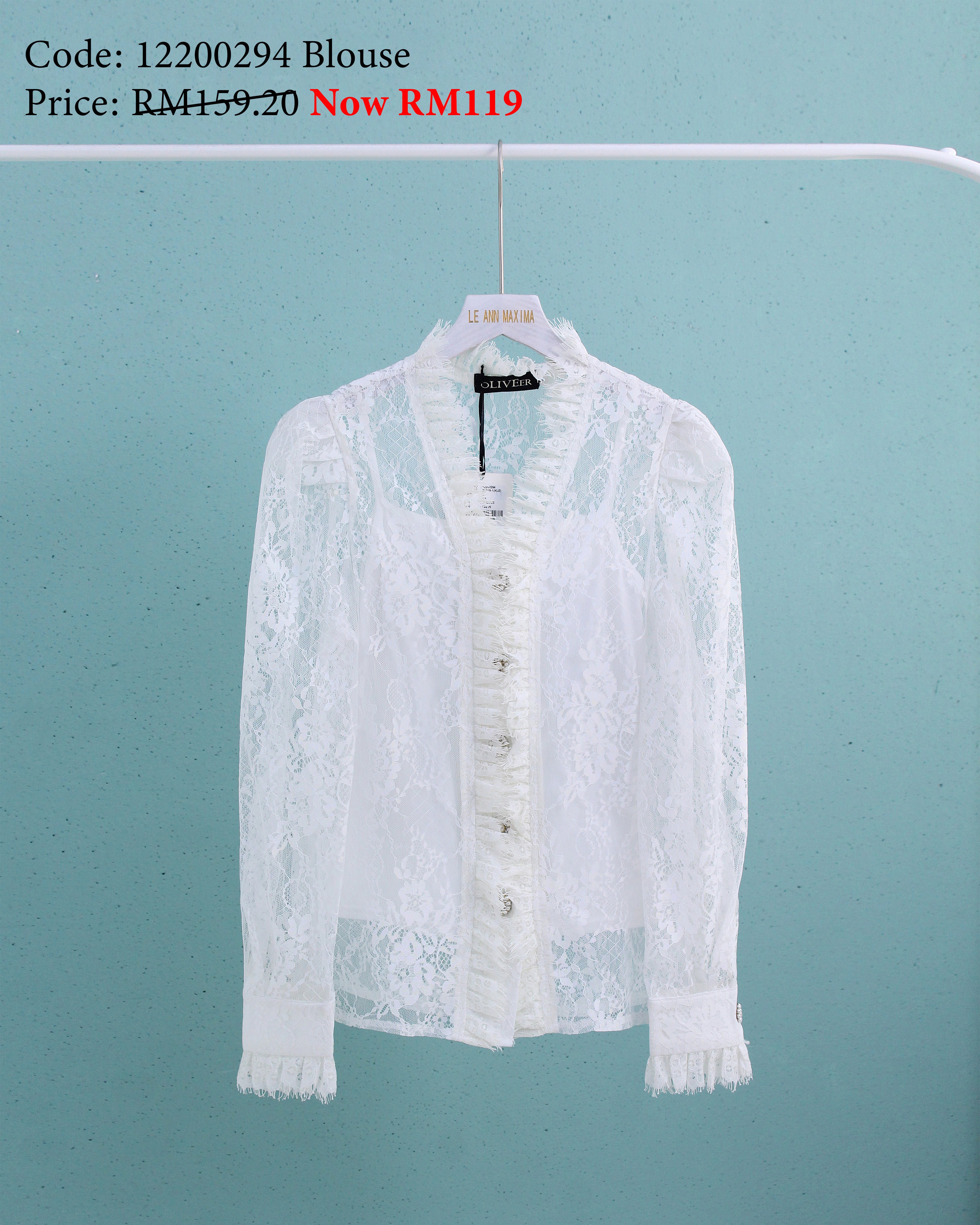 White lace blouse on a hanger against a light blue background