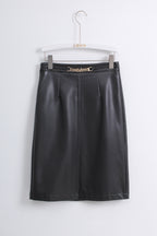 A black faux leather A-line skirt with pleated detailing and a gold-tone chain-link waistband, hanging on a white hanger against a light gray wall.