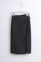 A black wrap-style pencil skirt with a side knot detail, hanging from a white hanger against a plain white wall.