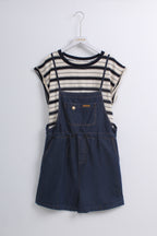 a navy blue denim overall romper layered over a cream and navy striped short-sleeve top.