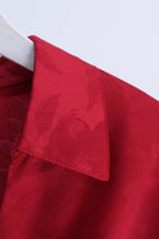 Close-up of a red collared shirt or blouse on a white hanger, showing the collar and upper chest area with a subtle tonal floral jacquard pattern.