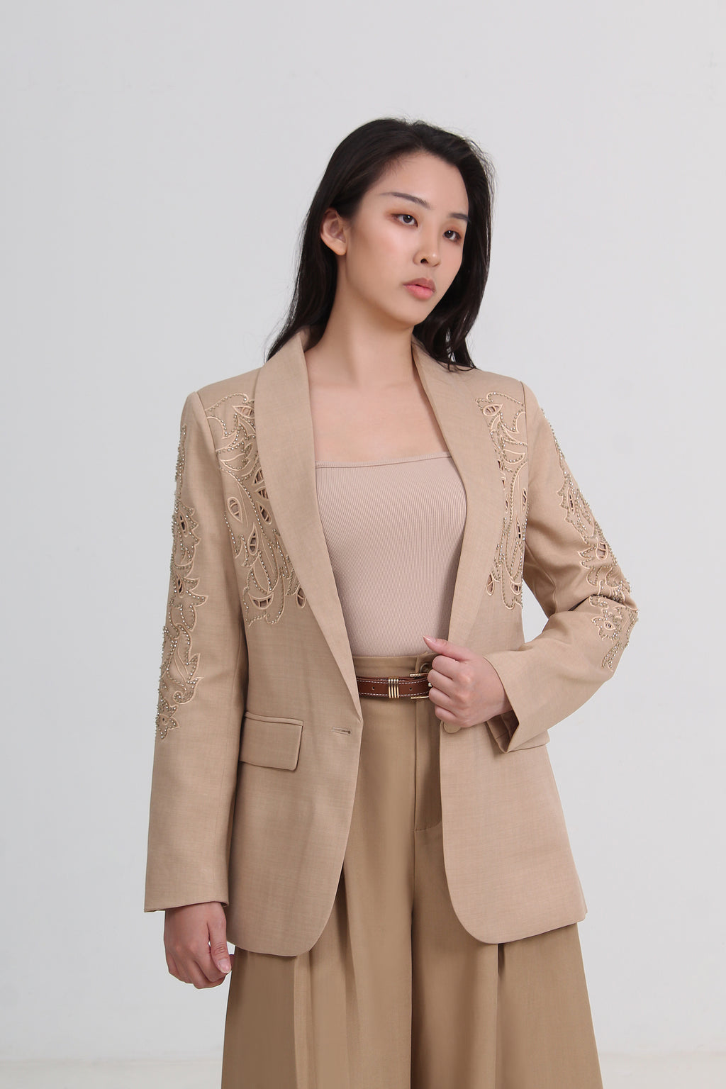 a beige tailored blazer with delicate floral embroidery on the lapels and shoulders, paired with a matching beige top and trousers by Le Ann Maxima
