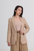 a beige tailored blazer with delicate floral embroidery on the lapels and shoulders, paired with a matching beige top and trousers by Le Ann Maxima