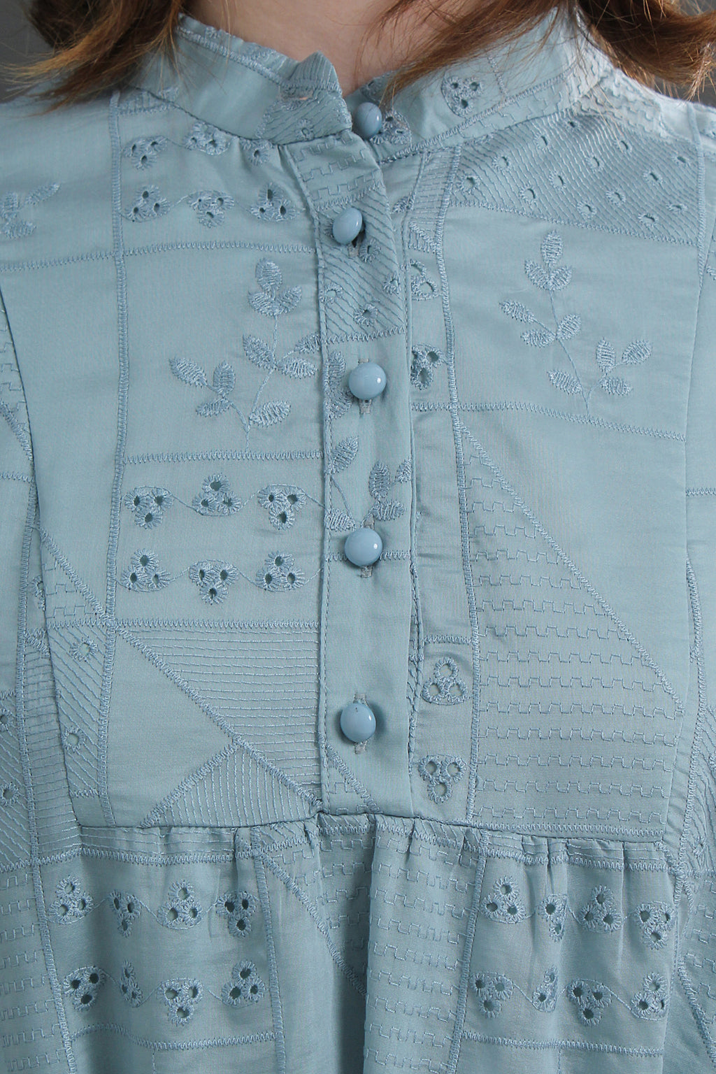 Light blue embroidered dress with buttons on a person wearing it.