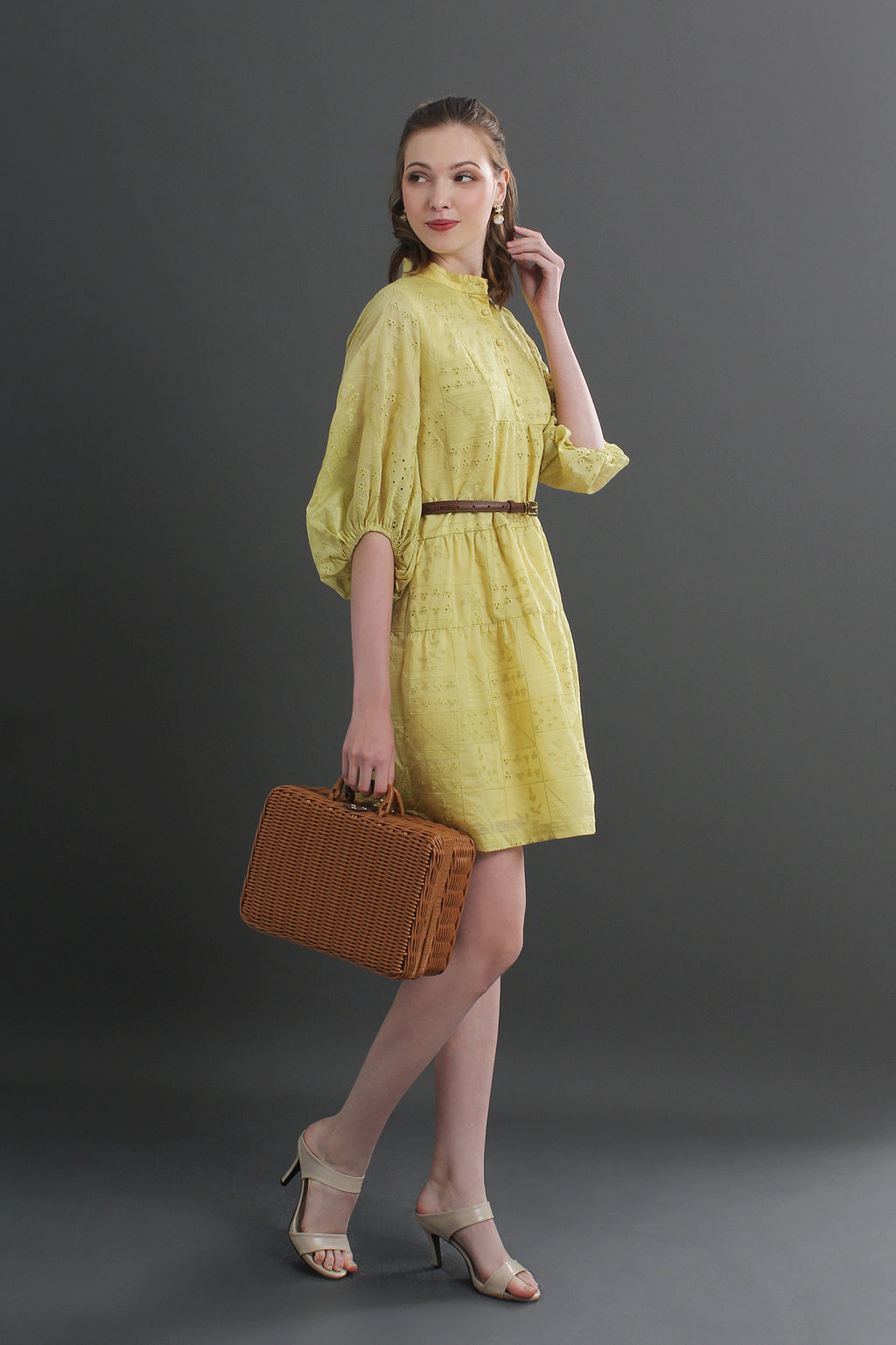 Woman in a yellow dress holding a brown suitcase