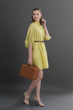 Woman in a yellow dress holding a brown suitcase
