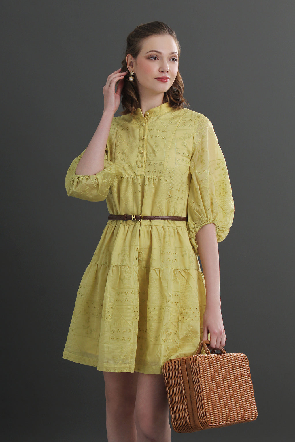 Woman in an eyelet yellow dress holding a brown bag