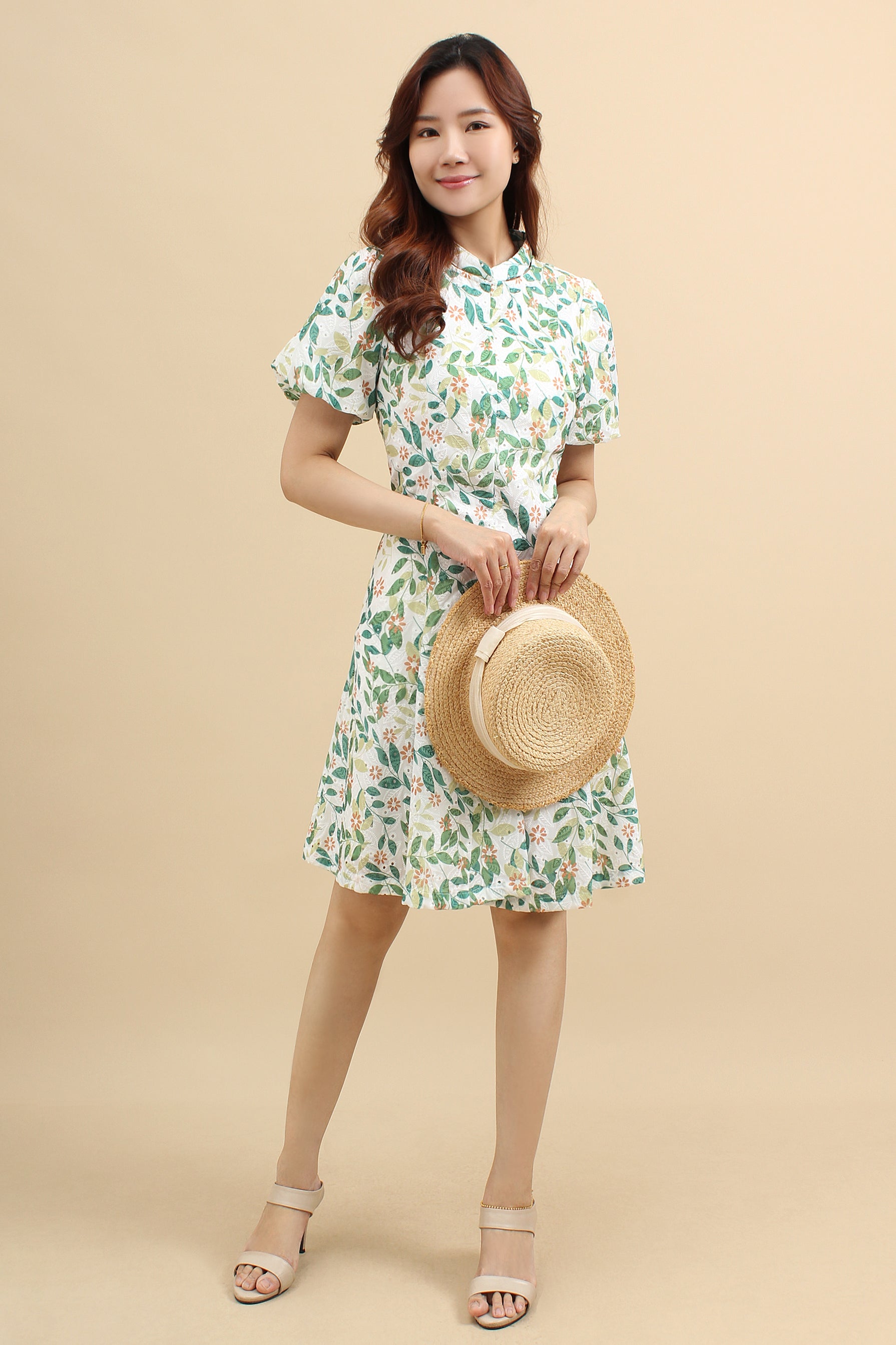 A woman wearing a green floral printed mini dress with that has cotton eyelet and short puff sleeves