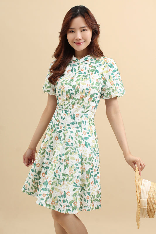 A woman wearing a green floral printed mini dress with that has cotton eyelet and short puff sleeves