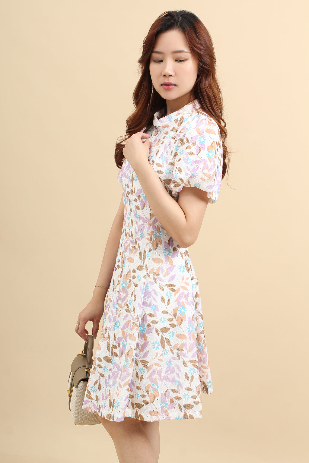 A woman wearing a purple floral printed mini dress with that has cotton eyelet and short puff sleeves