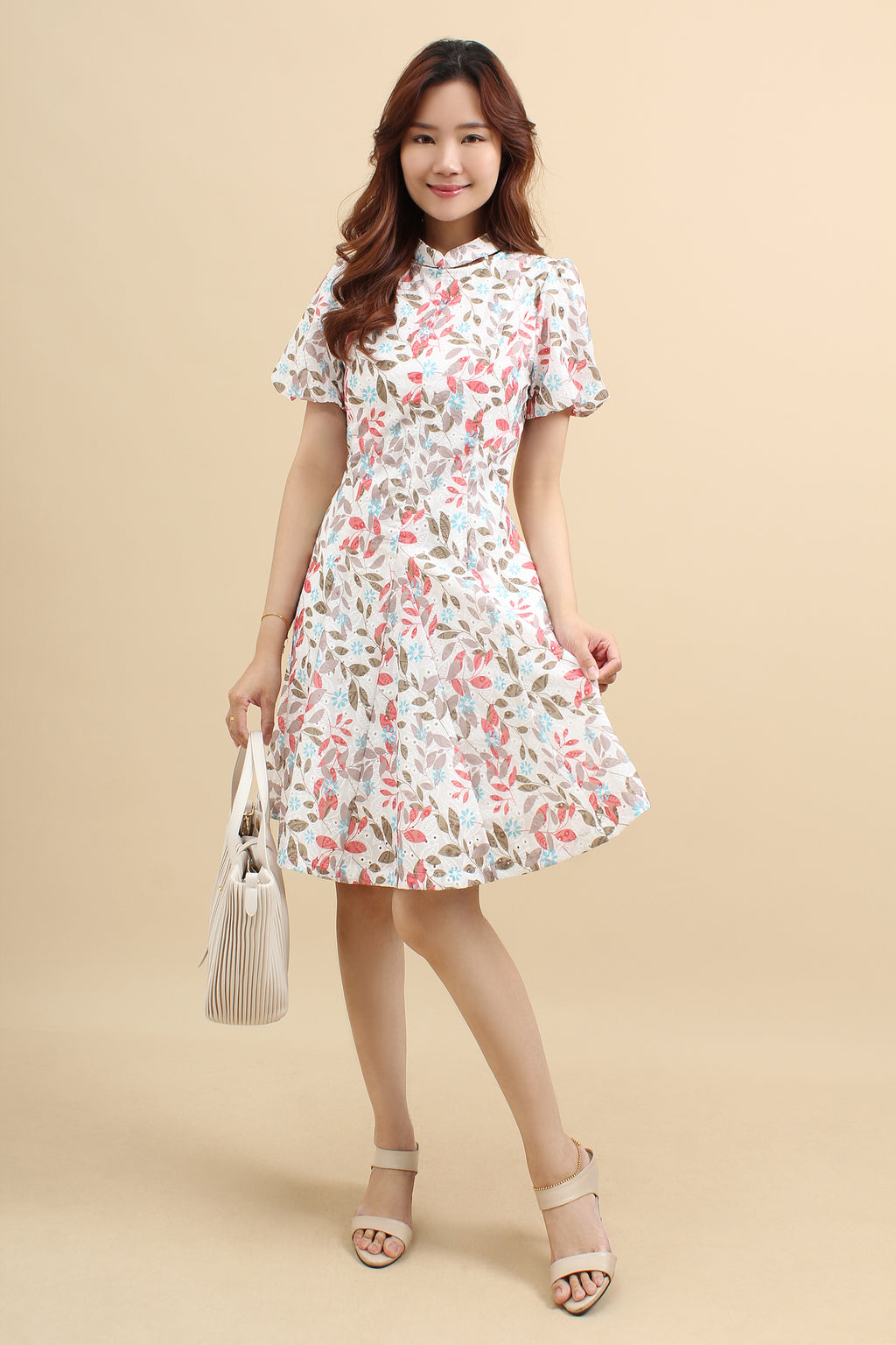 A woman wearing a red floral printed mini dress with that has cotton eyelet and short puff sleeves