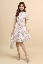 A woman wearing a red floral printed mini dress with that has cotton eyelet and short puff sleeves