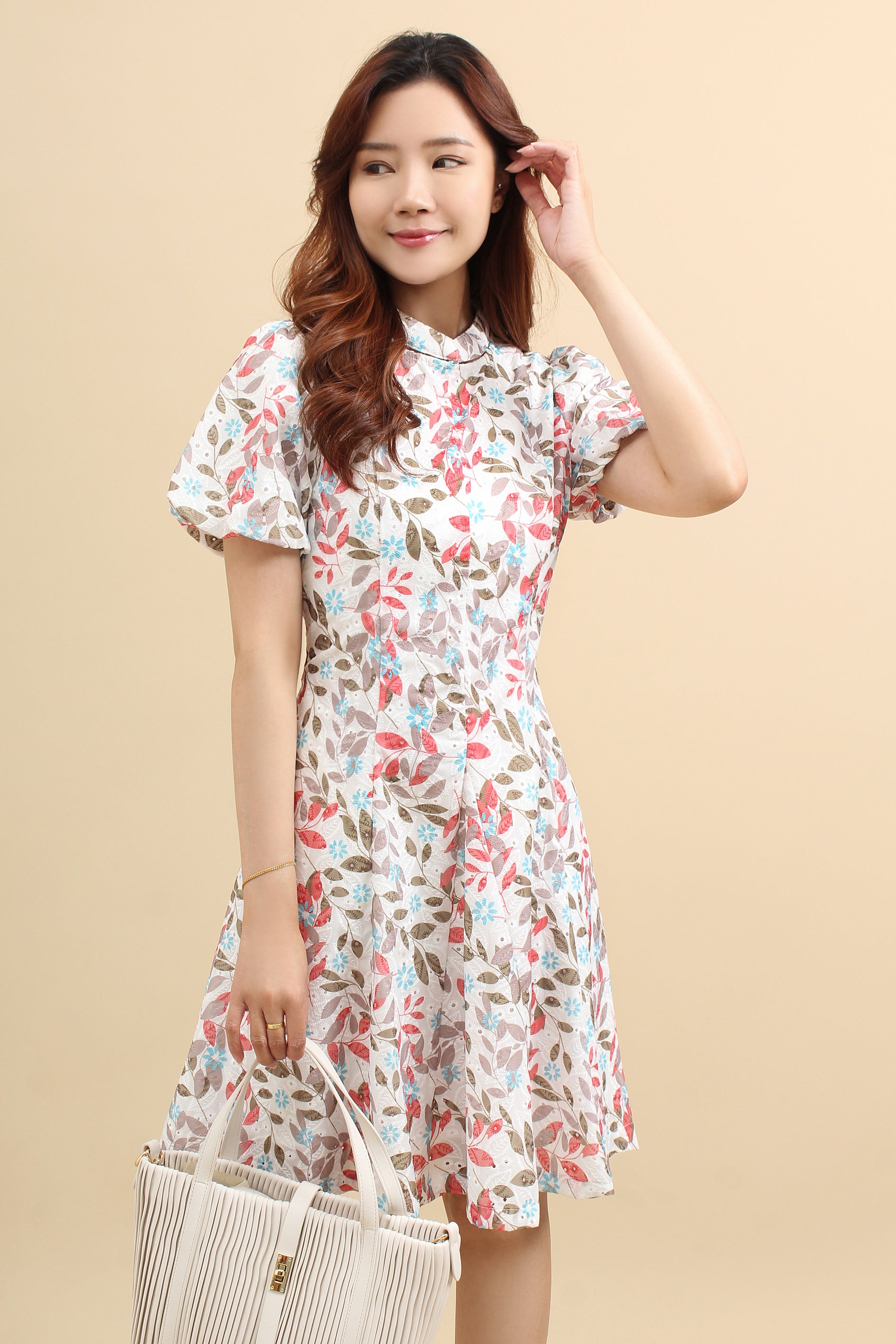 A woman wearing a red floral printed mini dress with that has cotton eyelet and short puff sleeves