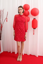 Woman wearing a red lace cheongsam with red lanterns and decorative sticks in the background