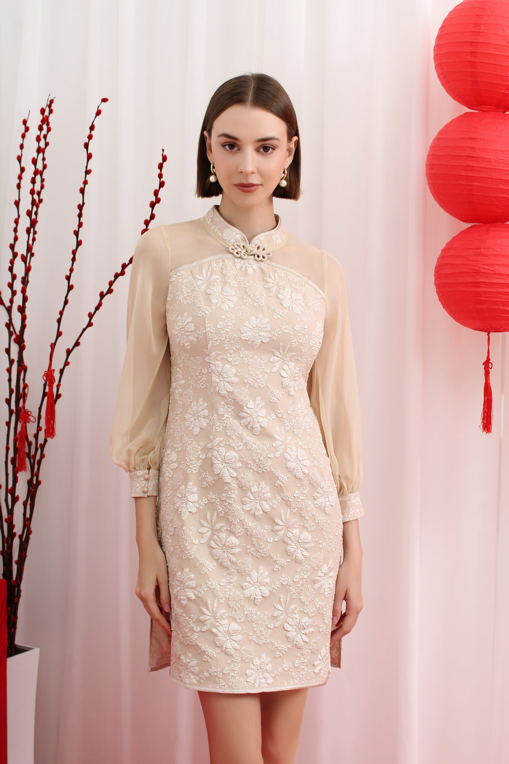 Woman wearing a light-colored cheongsam dress with floral patterns against a white background with red lanterns.