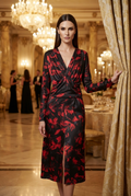 A woman models a long-sleeve wrap-style midi dress with a black base and red floral pattern