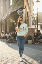 Woman walking on a street in front of a cafe with a 'Cafe Latte' sign wearing a snoopy and friends sweatshirt
