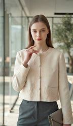 A woman wearing a cropped cream-colored jacket with intricate floral embroidery