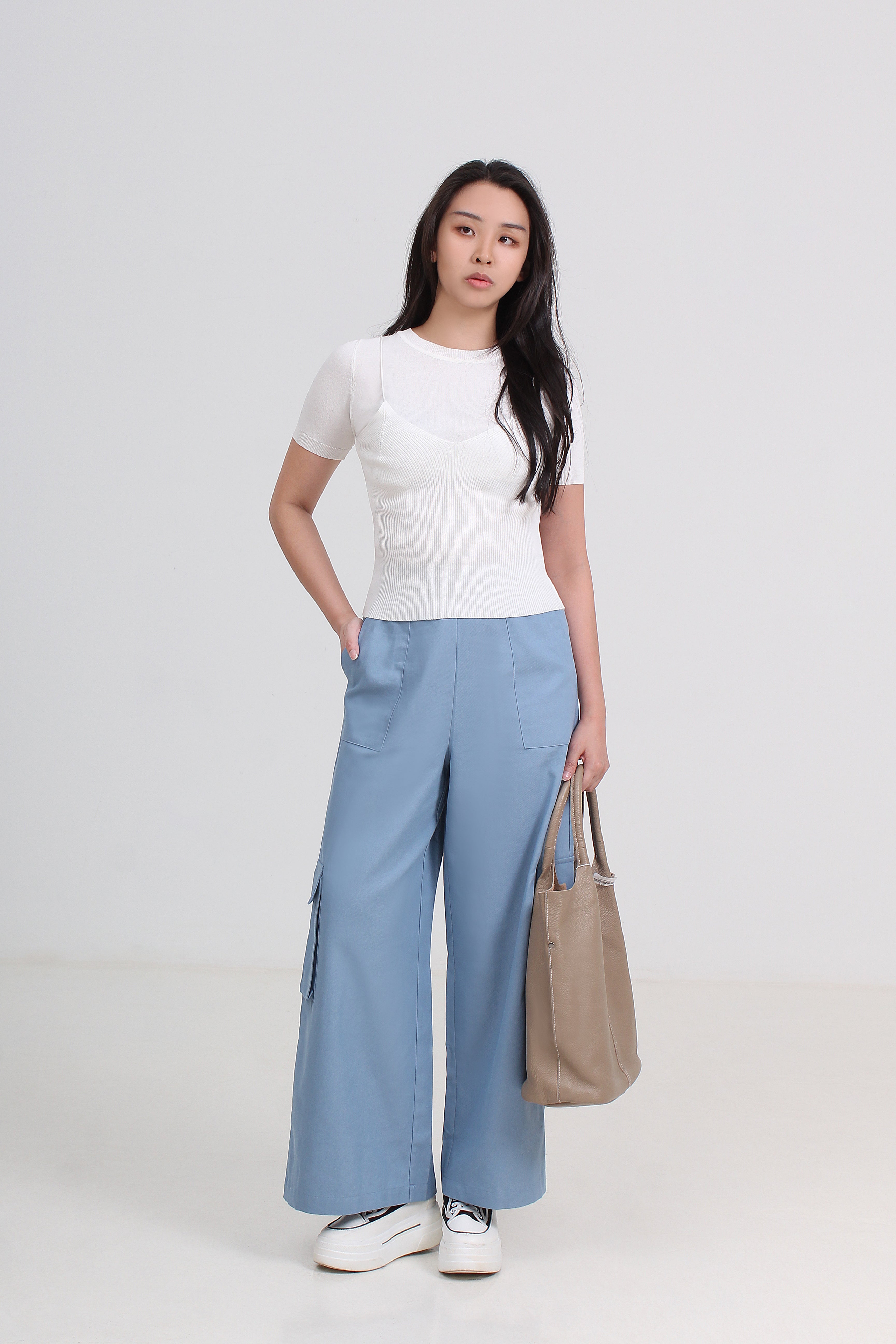 A woman modeling a white short-sleeve top and light blue wide-leg cargo pants.