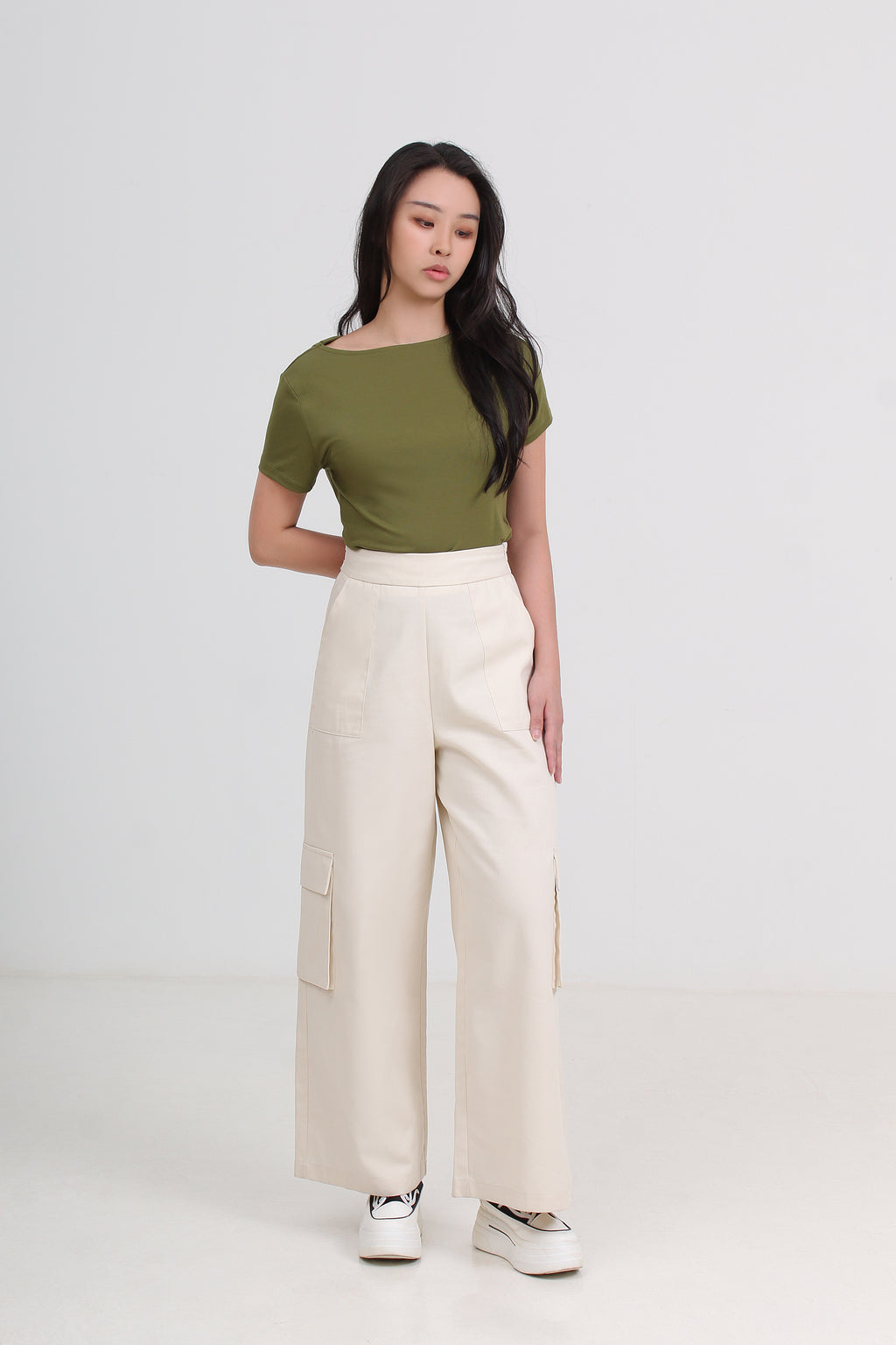 A woman modeling a short-sleeve olive green top and high-waisted cream wide-leg cargo pants.