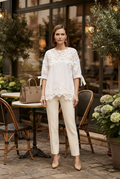 white lace-trimmed short-sleeve top and cream-colored straight-leg trousers. 