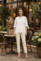 white lace-trimmed short-sleeve top and cream-colored straight-leg trousers. 
